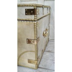 an old trunk with gold rivets is sitting on the floor in front of a white wall