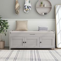 a white bench sitting in front of a mirror next to a potted plant on top of a rug