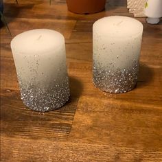 two white candles sitting on top of a wooden table