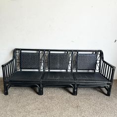 a black bench sitting on top of a carpeted floor next to a white wall