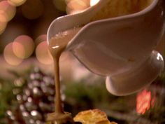 a spoon pouring liquid into a cup on top of a table with christmas decorations in the background