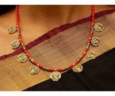 Product Description :  High quality Oxidized Gold Goddess Durga Coins with Red Coral beads Necklace with adjustable necklace dori for perfect fitting. A perfect choice for your jewellery collection. Suitable for Wedding, ethnic wear, festive and party wear. A beautiful gift for your loved ones. This product is especially handmade for you after receiving the order and takes 4 to 5 man hours to complete, hence slight imperfections are expected which is not a defect.  Slight color variation of the product may occur due to photographic light effect. Necklace Weight : 55 gms Dimensions : Necklace Length (w/o dori) - 22 cm, Dori Length - 26 cm Material : Alloy metal, Oxidized Gold, Faux Coral beads Product Care :  Avoid contact with body spray, chemicals & water. Clean with soft cloth after use Red Temple Necklace With Round Beads As Gift, Red Temple Necklace With Round Beads For Gift, Red Beaded Temple Necklace Gift, Orange Beaded Necklaces For Festivals, Red Spiritual Jewelry For Diwali, Adjustable Red Jewelry For Navratri, Navratri Necklaces With Latkans And Round Beads, Orange Jewelry For Diwali Puja, Handmade Red Temple Necklace For Gifts