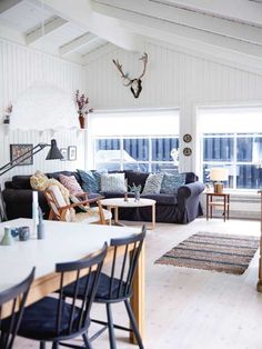 a living room filled with furniture next to a kitchen and dining room table in front of two windows