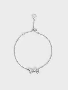 Our Paige bracelet is also available in a stunning silver finish. With its classic ribbon charm, this delicate piece is ideal for fashion lovers who want to embrace the coquette trend in an understated manner. Wear yours layered with other silver bracelets for a stylishly stacked look. Alternatively, style it with our matching Paige necklace and stud earrings for a complete set and polished look. Chic Silver Chain Bracelet For Formal Occasions, Sterling Silver Adjustable Delicate Chain Bracelet, Elegant Metal Charm Bracelet With Delicate Chain, Chic Sterling Silver Bracelet As A Gift, Minimalist Sterling Silver Chain Bracelet For Party, Chic Sterling Silver Bracelet Gift, Sterling Silver Bracelets With Adjustable Chain For Party, Dainty Sterling Silver Chain Bracelet For Party, Elegant Adjustable Bracelets With Bow Detail