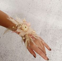 a woman's hand wearing a flower and feather wrist corsage