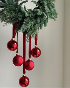 red ornaments hanging from a christmas tree branch