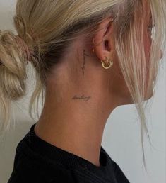 a woman with a tattoo on her neck and behind her ear is looking to the side