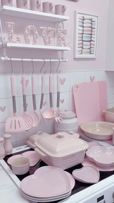 a kitchen with pink dishes and utensils hanging on the wall above the stove