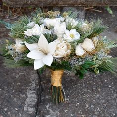 a bouquet of white flowers and greenery on the ground