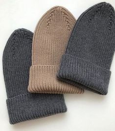 three knitted mittens sitting next to each other on top of a white surface