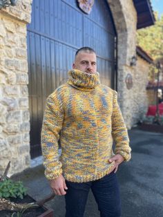 a man standing in front of a garage door wearing a yellow and blue knitted sweater