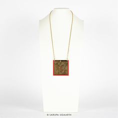 Gold and Red Acrylic Maze Necklace. Acrylic, antique gold finish stainless steel chain.Pendant height: 3 in. / 7.5 cms.Pendant width: 3 in. / 7.5 cms.Necklace length: 15.5 in. / 40 cms. NOTE:Each handmade accessory may have slight irregularities or imperfections, which add to its charm, while ensuring that you have a unique piece. All jewelry measurements are approximate. COLOR:Every effort is made to display the colors of each accessory as accurately as possible. However, each monitor reproduce Brass Medallion Necklace As Gift, Brass Medallion Necklace With Chain As Gift, Gold Chain Medallion Necklace, Gold Chain Medallion Necklace As Gift, Handmade Rectangular Brass Necklace, Red Long Necklace For Gift, Red Metal Jewelry With Gold Chain, Handmade Brass Necklace With Square Pendant, Red Gold Chain Metal Jewelry