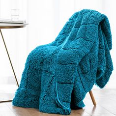 a blue blanket sitting on top of a wooden floor next to a table and chair