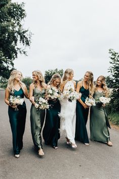 bridesmaids in green dresses walking down the road with bouquets on their laps