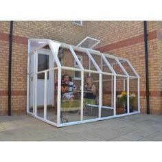 a small white greenhouse sitting on the side of a building