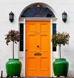 two large green vases sitting in front of a yellow door on a white building