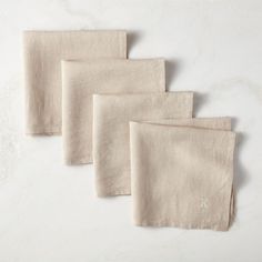 four linen napkins with monogram on them sitting on a white countertop top