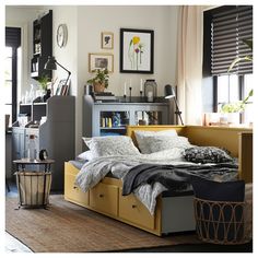 a bed sitting in the middle of a living room next to a dresser and window