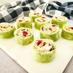 there are many rolls that have been made with green and red food wrappers on the cutting board