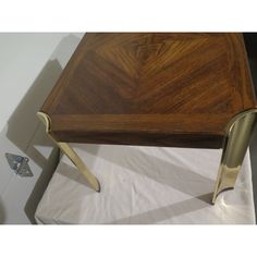 a wooden table with two metal legs and a white sheet on the floor next to it