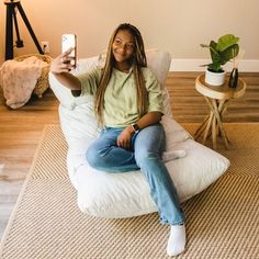 a woman sitting on a bean bag chair taking a selfie with her cell phone