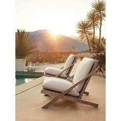 two lounge chairs sitting on top of a patio next to a swimming pool