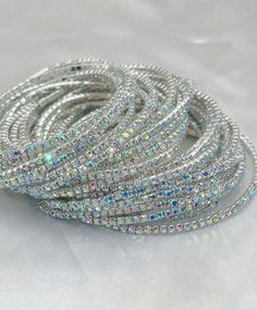 The Jeweled Bracelet Stack is an ultra-fine and fashionable set of 11 elastic bracelets, each covered in dazzling AB rhinestones. Perfect for any occasion, from parties and gatherings to banquets and daily wear, these bracelets add a touch of sparkle and sophistication to any outfit. Designed for women who love to make a statement, this set offers versatile styling options with its eye-catching elegance. Diameter: 2" Trendy Crystal Bracelets For Party, Trendy Stackable Beaded Bracelets For Party, Trendy Crystal Bracelets With Rhinestones, Elegant Stackable Stretch Bracelet For Party, Glamorous Crystal Bracelets For Party, Glamorous Sparkling Bracelets For Party, Glamorous Sparkling Bracelet For Party, Trendy Party Bracelets With Rhinestones, Silver Rhinestone Bracelets For Party