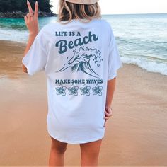 Tshirt Is Soft And Unisex Sizing For Loose Fit. For A Tighter Fit Size Down One. Life Is A Beach So Make Some Waves Design On Back Of White Tshirt And Front Pocket Has Make Some Waves Design. Beachy T Shirts, White Print T-shirt For Summer, White Vsco T-shirt With Text Print, White Summer T-shirt With Text Print, Vsco Style Short Sleeve T-shirt With Text Print, Vsco Style T-shirt With Text Print, Summer White Print Short Sleeve Top, White Print Short Sleeve Summer Top, White Slogan Top For Beach Season