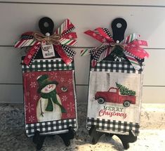 two christmas gift bags with snowman and truck on them, hanging from the wall