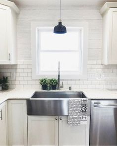 a kitchen with white cabinets and stainless steel dishwasher in the corner, next to a window