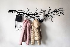 three coats hanging on the wall next to a hat rack