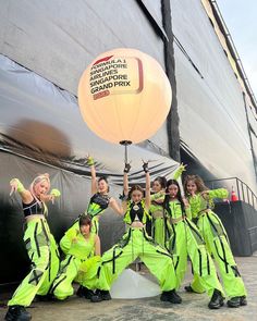 a group of young women standing next to each other in front of a large balloon