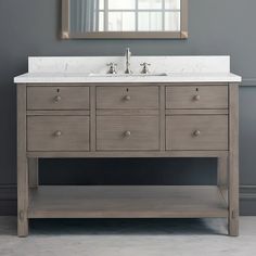 a bathroom vanity with two sinks and a mirror on the wall above it in a gray room