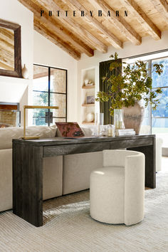 a living room filled with furniture and a large window covered in wooden beams on the ceiling