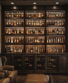 a room filled with lots of bottles of liquor on shelves next to a chair and ottoman