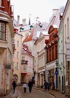 several people walking down an alley way between two buildings with red roof tops on top