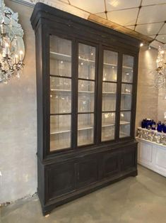 an old china cabinet with glass doors and chandelier hanging from it's ceiling