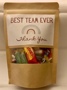 a bag filled with lots of candy sitting on top of a white countertop next to a sign that says, best team ever thank you