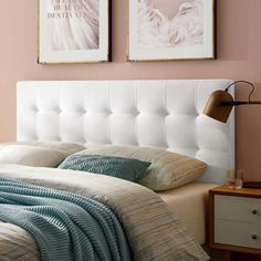 a bedroom with pink walls and white headboard, two pictures on the wall above the bed