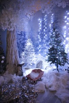 a room filled with lots of snow covered trees and lights on the ceiling, surrounded by white fur