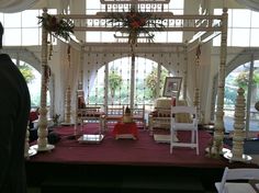 a man standing in front of a stage set up for a wedding ceremony with white chairs and red carpet