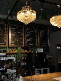 a coffee shop with chandeliers hanging from the ceiling and menus on the wall