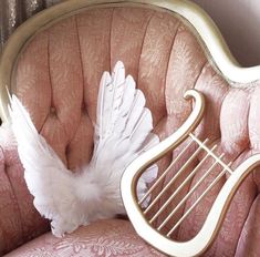 a white bird sitting on top of a pink chair next to a golden lyre