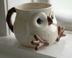 a ceramic owl mug sitting on top of a window sill