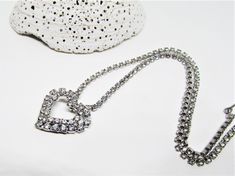 "A pretty vintage 1950's silver heart pendant necklace with sparkling crystals. It features a open heart pendant with a double row of glimmering clear pave rhinestones. The pendant is attached to a sparkling cup chain with tiny prong-set rhinestones. The chain is 14\" choker length with an additional 1\" length to adjust it longer. The clasp is a hook set with a pretty, sparkling crystal. The style would compliment most outfits and be perfect for everyday as well as special occasions. A perfect, Silver Rhinestone Necklace For Wedding On Valentine's Day, Silver Rhinestone Heart Pendant Necklace For Wedding, Silver Heart Pendant Rhinestone Necklace For Weddings, Vintage Heart Pendant Jewelry For Party, Vintage Heart Pendant Necklace For Party, Silver Heart Rhinestone Necklace For Wedding, Silver Heart-shaped Rhinestone Necklace For Wedding, Silver Heart Shaped Rhinestone Necklace For Wedding, Vintage Heart Necklace For Valentine's Day Party