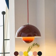 a lamp hanging from the ceiling in a room with white walls and colorful circles around it