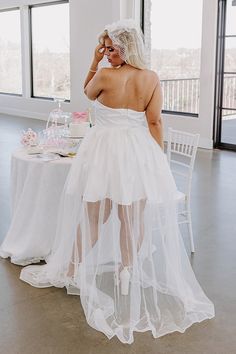 - This gorgeous dress is giving fairytale vibes! - Material with a satin finish overlaid by tulle - A built-in partial lining ending upper thigh length - Floral accents - A straight strapless neckline with a interior non-slip strip - Built in padding - Back zip closure - A flowy silhouette that ends in a straight maxi length hemline Sheer Tulle Corset Dress For Wedding, Strapless Sheer Tulle Corset Dress, Sheer Strapless Wedding Dress, White Sheer Satin Dresses, Strapless Sheer Wedding Dress, White Satin Dress With Detachable Train, Strapless Organza Dress With Tulle Skirt, White Strapless Sheer Dress, White Strapless Satin Wedding Dress