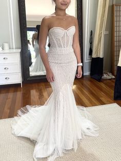 a woman standing in front of a mirror wearing a wedding dress