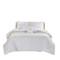 a bed with white and purple polka dot sheets, pillows and a flower on it