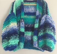 a blue and green sweater hanging on a wooden hanger